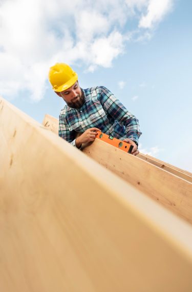 worker-with-hard-hat-level-checking-roof-timber-house